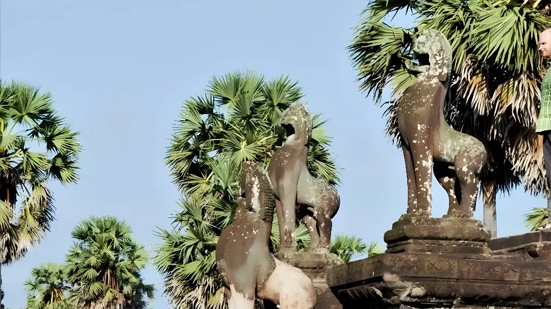 Stone statues with palm trees in background.